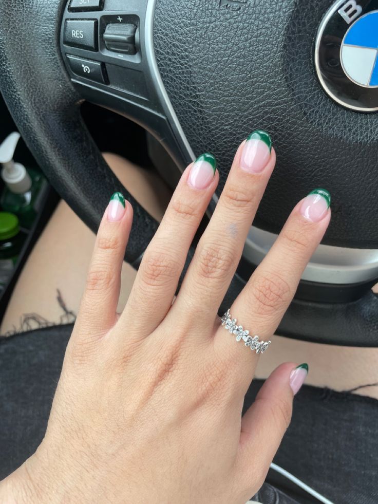 Sophisticated French Manicure with Rich Green Tips and Delicate Jewelry.