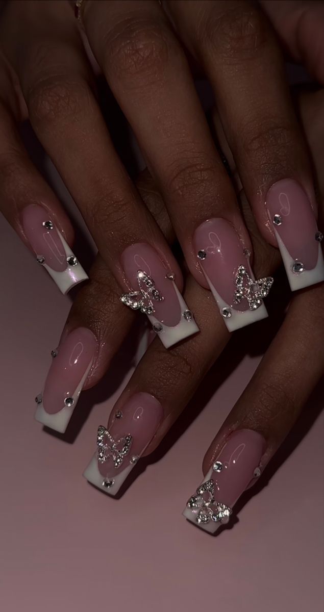 Elegant Long Square Nail Design: Soft Pink Polish, White Tips, Rhinestones, and Butterfly Motifs.