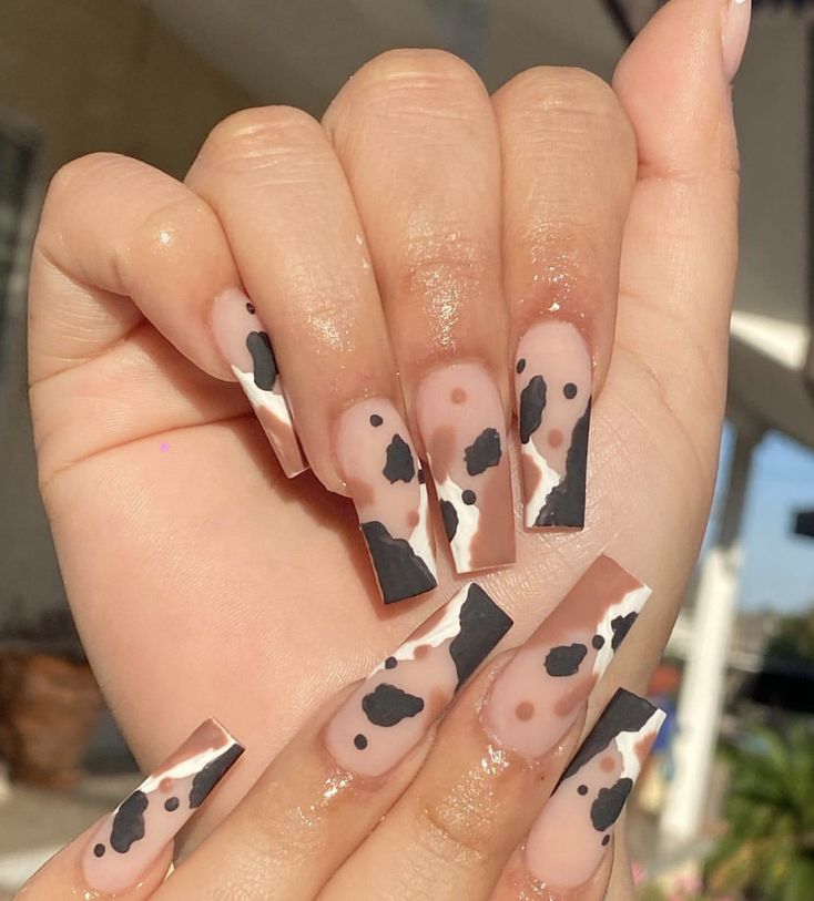 Trendy Cow Print Nails: A Chic Blend of Neutral Tones and Bold Black Accents.