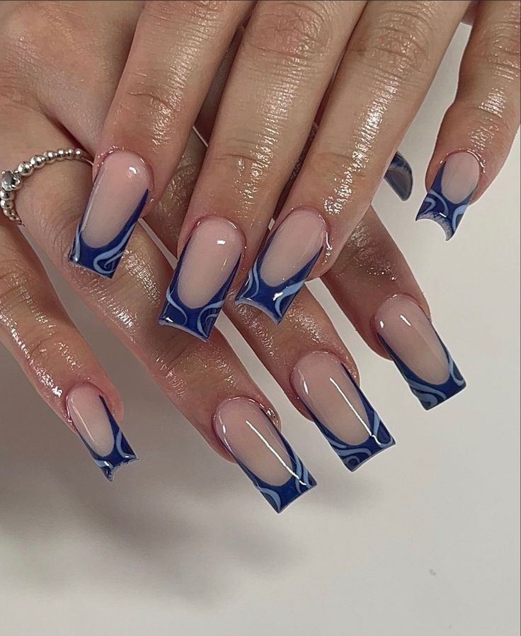 Sophisticated Nail Design: Soft Nude Base with Striking Blue Tips and Artistic Swirl Pattern