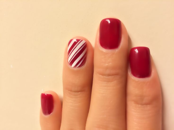 Festive Burgundy Nail Design with Playful Striped Accent for Seasonal Celebrations.