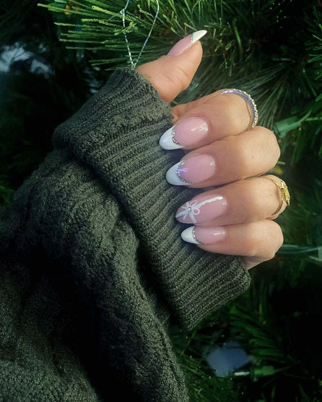 Chic Holiday French Manicure with Bow Accent and Shimmering Base.