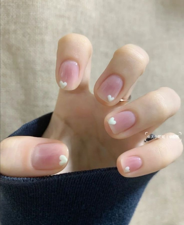 Charming Heart-Shaped Nail Design: A Delicate Pink Base with Subtle White Hearts for Any Occasion.