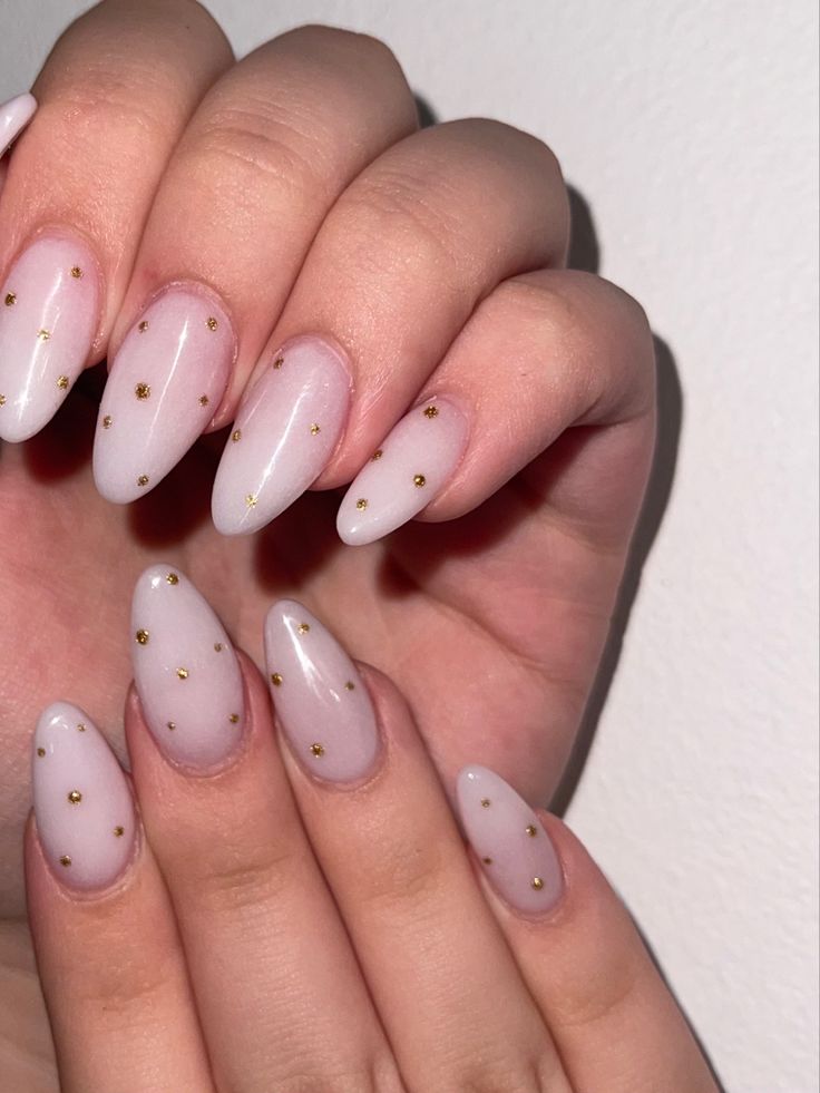 Sophisticated Almond-Shaped Nail Design with Translucent Pink Base and Gold Studs.