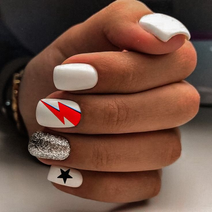 Trendy Nail Art: Bold Red Lightning, Sleek White Base, Sparkling Silver Glitter, and Playful Black Star Accents.