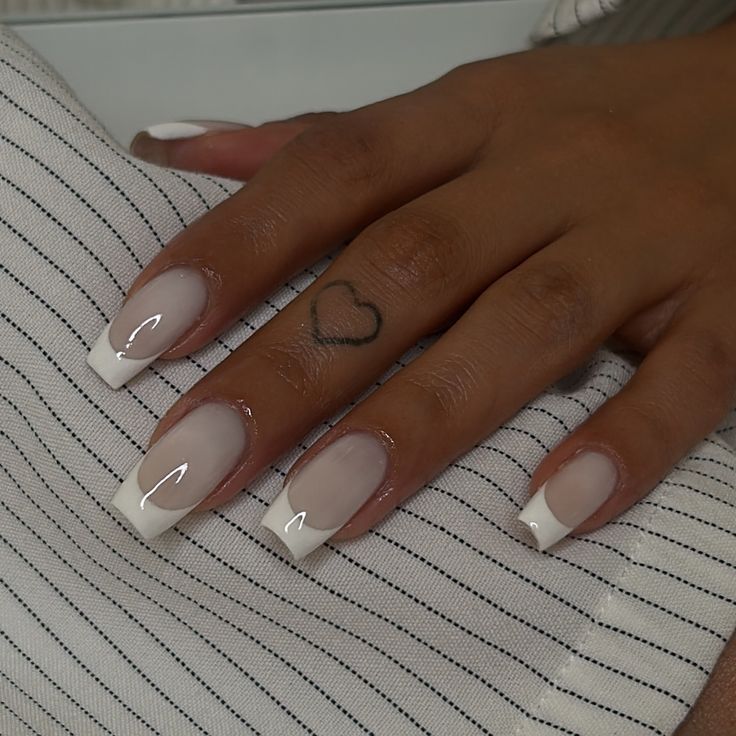 Timeless Elegant French Manicure with Soft Nude Base, Crisp White Tips, and Playful Heart Tattoo.