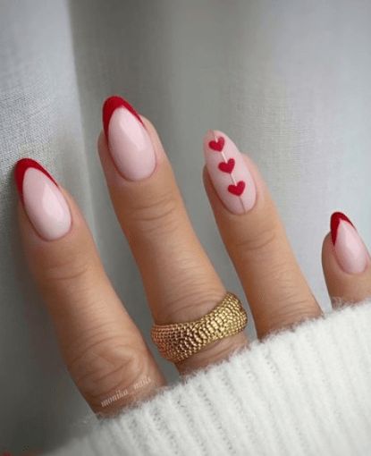 Elegant Almond Nail Design: Soft Pink Base with Bold Red Accents and Heart Motifs.