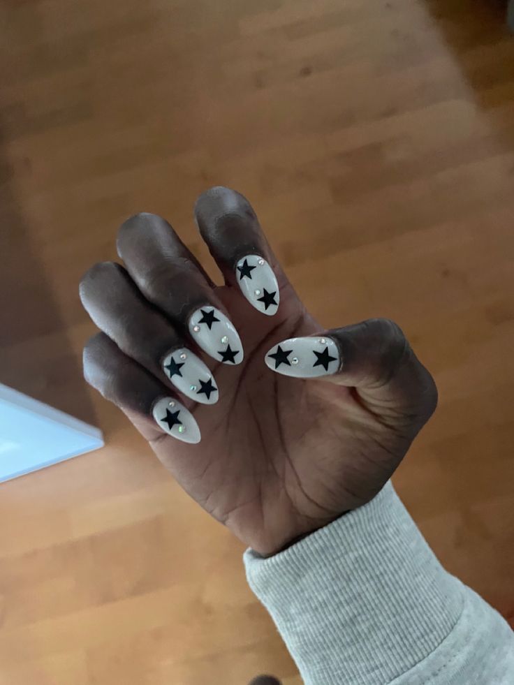 Chic Nail Design: White Base with Bold Black Star Patterns for Playful Elegance