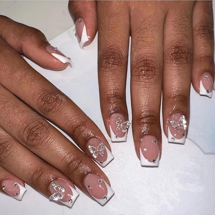 Sophisticated Nude Nail Design with Whimsical Butterfly Motifs and Sparkling Rhinestones.