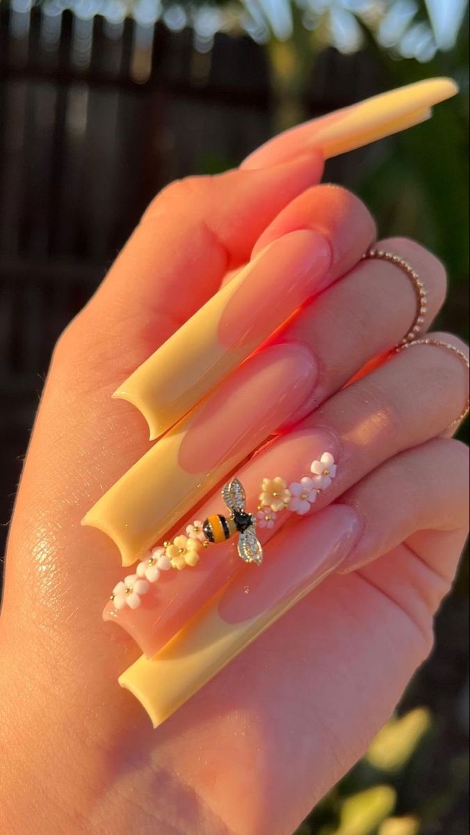 Whimsical Almond-Shaped Nail Design: Soft Peach and Vibrant Yellow with Floral Accents and Bee Motif.