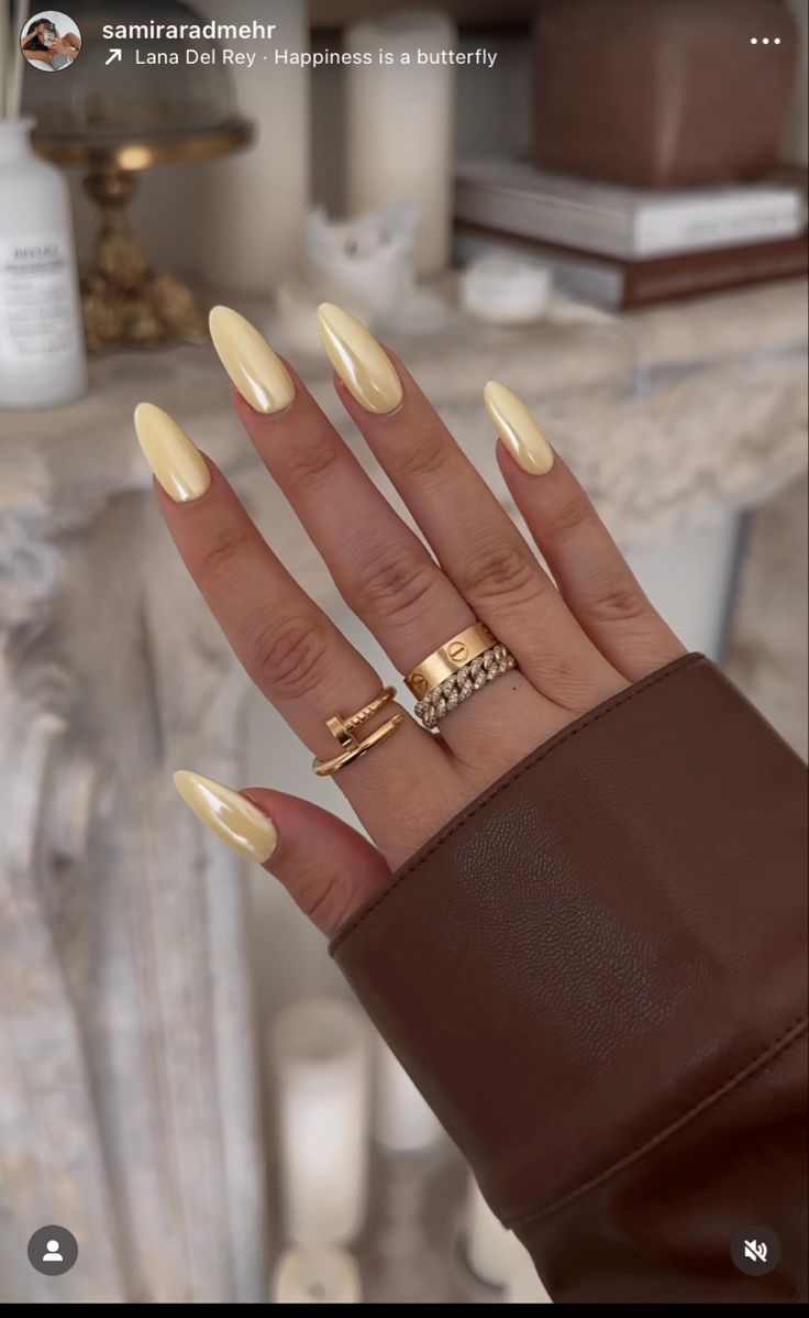 Trendy Chic Almond-Shaped Nails in Soft Yellow with Elegant Gold Accents.