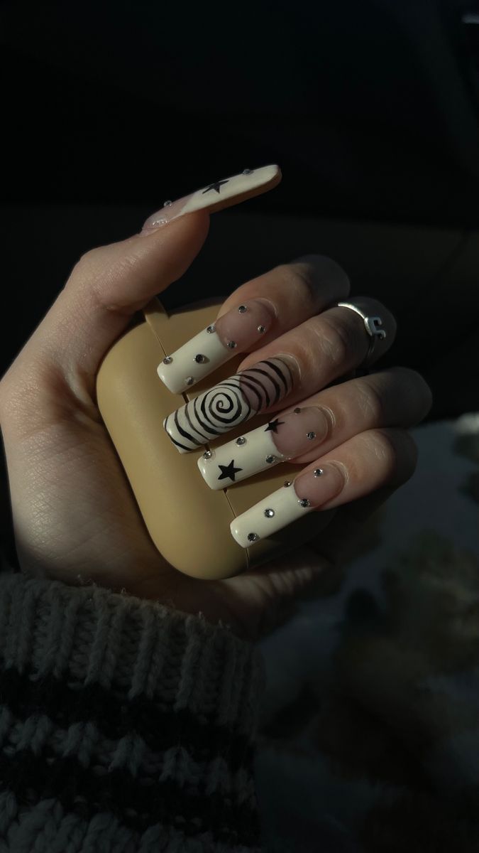 Chic Beige and Black Nail Design with Unique Patterns and Gem Accents.