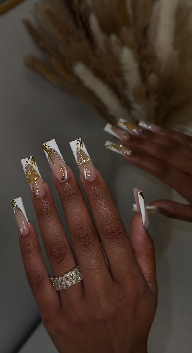 Sophisticated Nail Design: Nude and White Tips with Intricate Golden Accents and Sparkling Details.