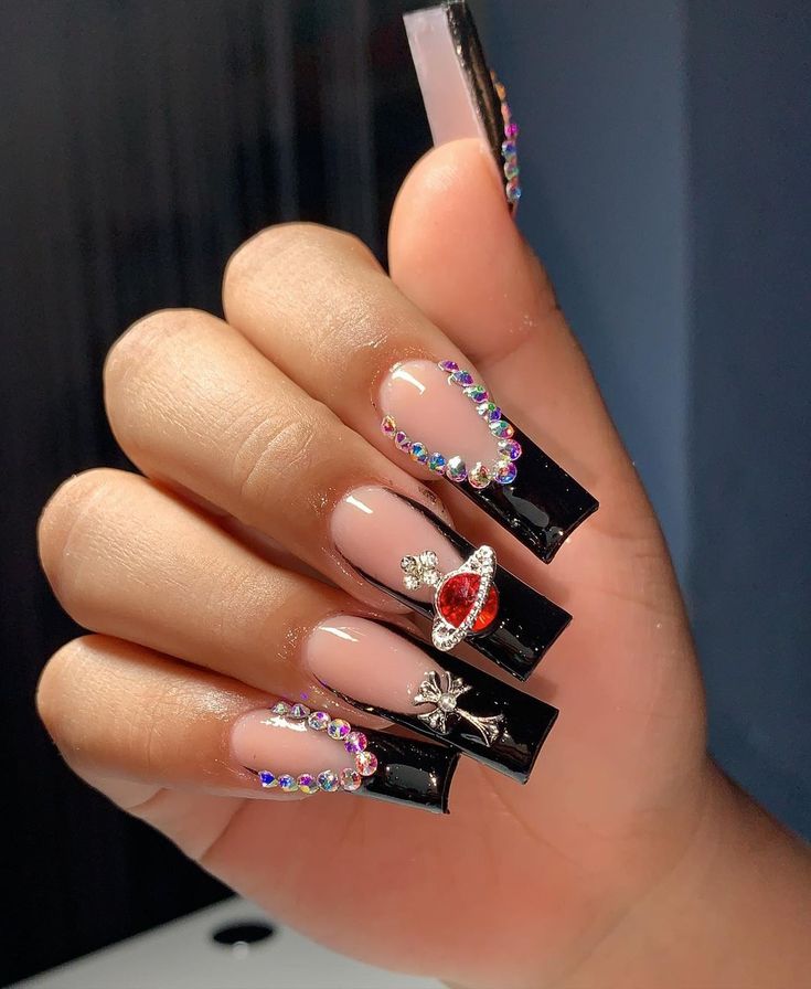 Glamorous Nail Art: Glossy Black and Nude Design with Rhinestones and Charms.