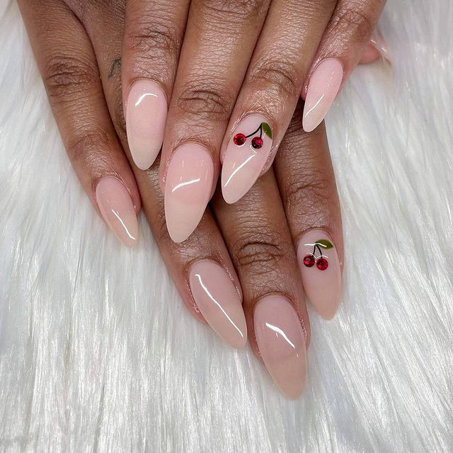 Chic Almond-Shaped Nude Nails with Playful Cherry Accents and Glossy Finish.