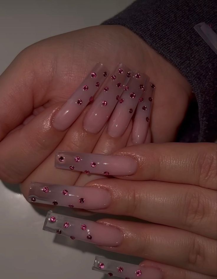 Sophisticated Nail Design: Elongated Clear Tips with Sparkling Pink Rhinestones on a Chic Nude Base.