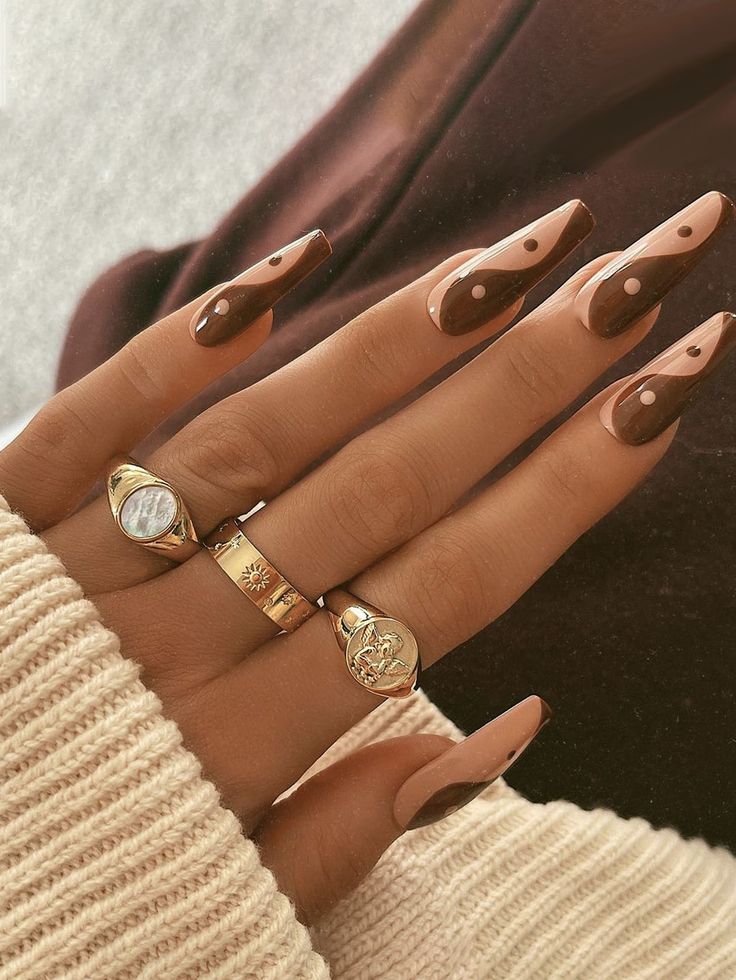 Chic Almond-Shaped Nail Design with Dark Brown and Nude Shades Enhanced by Playful Dot Patterns and Complementing Rings.