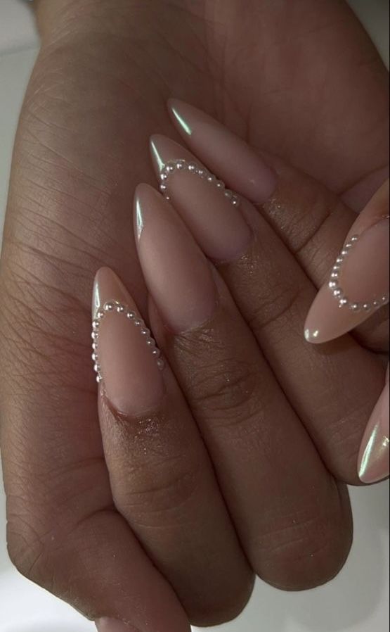 Sophisticated Elongated Almond Nail Design with Nude Base, Shimmering Silver Tips, and Pearl Accents.