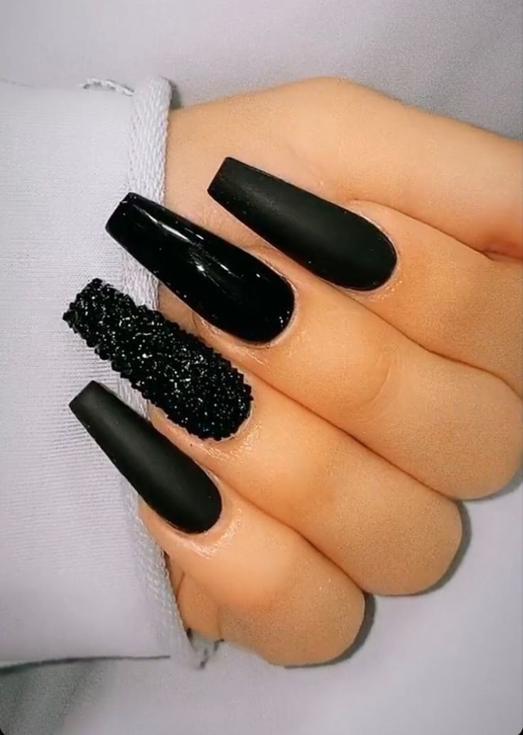 Chic Matte Black Nail Design with Glamorous Textured Accent.