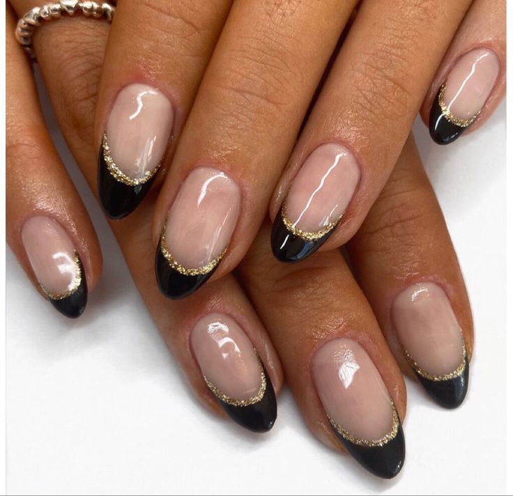 Chic Nail Design: Nude and Black Elegance with Glamorous Gold Accents.