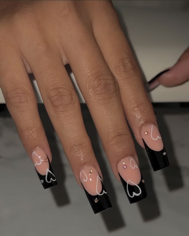 Chic Nail Design: Elegant Nude and Black with Heart Outlines and Gem Accents