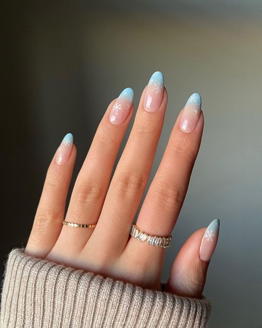 Elegant Winter Nails: Soft Pink and Icy Blue Gradient with Snowflake Designs.