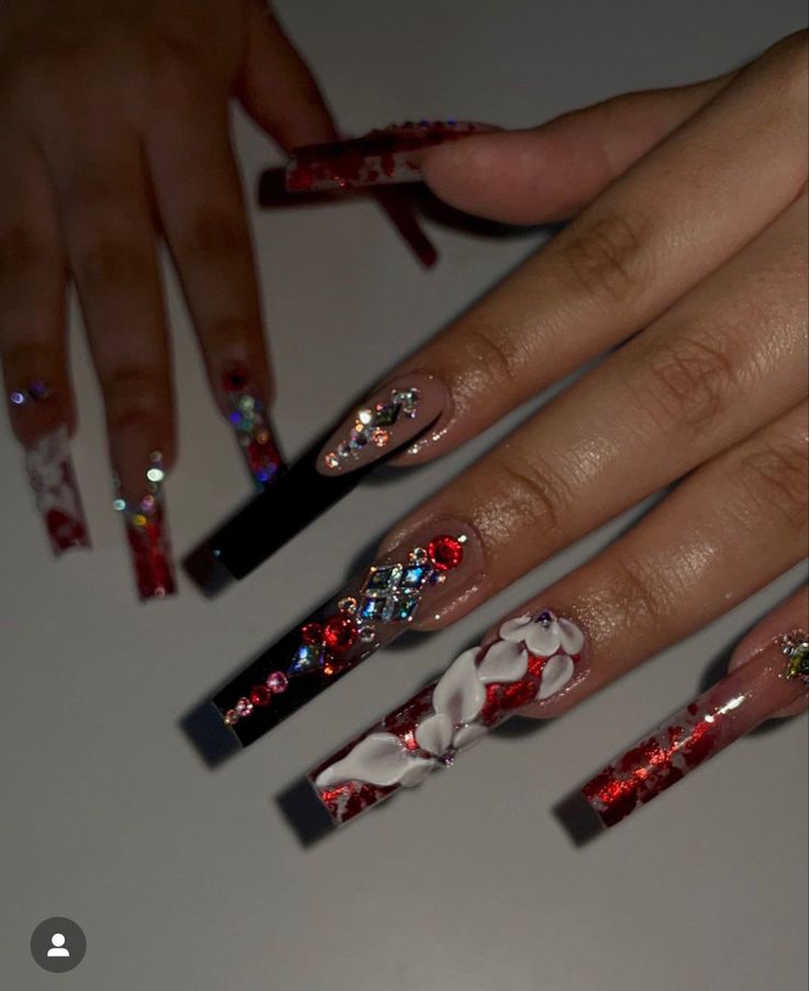 Glamorous Elongated Stiletto Nail Design with Red and White Floral Patterns and Rhinestones.