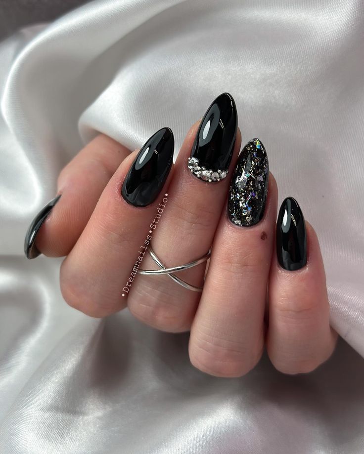 Chic Black Almond Nails with Glitter Tips and Rhinestone Accents.