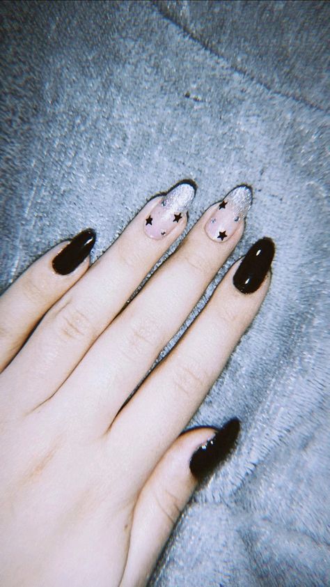 Whimsical Celestial Nail Design: Dark Glossy Black and Delicate Nude with Glitter Star Accents.