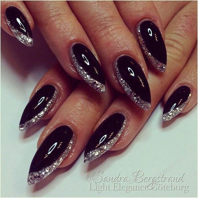 Sophisticated Black Almond Nails with Sparkling Silver Tips for Glamorous Occasions.