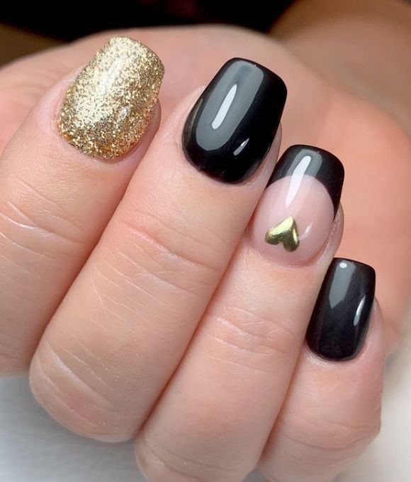 Elegant Chic Nail Design: Glossy Black and Sparkling Gold with Heart-Shaped Detail.