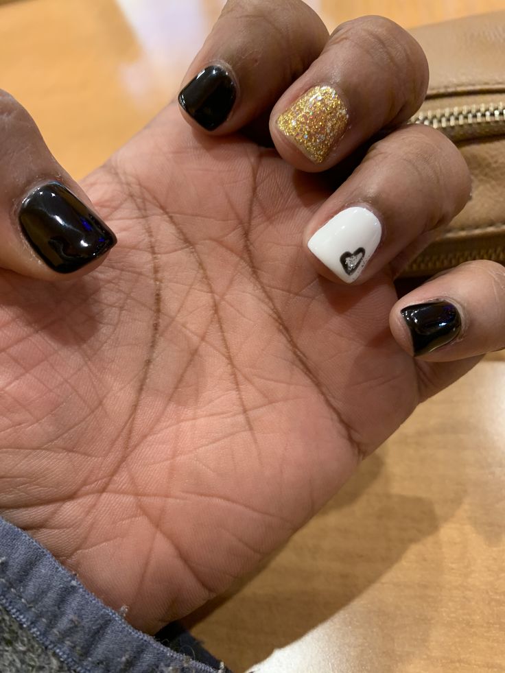 Chic Nail Design: Bold Black and White with Gold Accent and Heart Motif