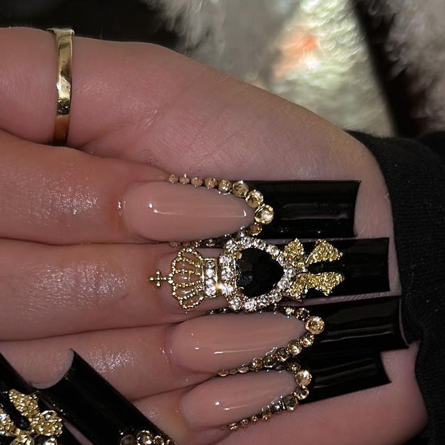 Chic Nail Design: A Regal Blend of Nude, Bold Black, and Gold Embellishments.