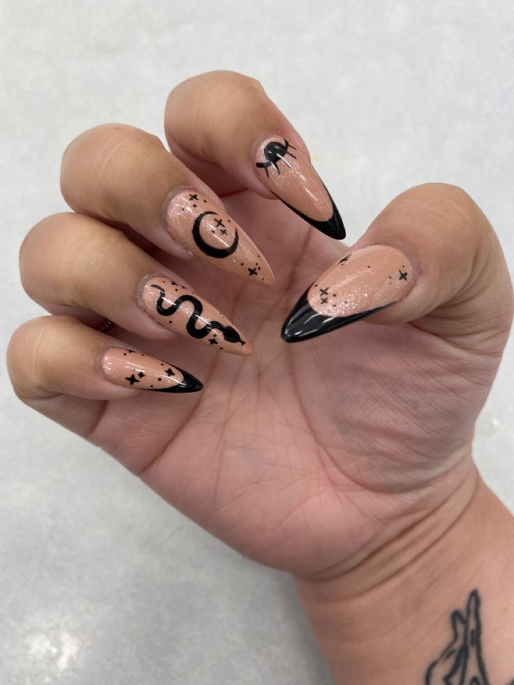 Edgy Nude and Black Nail Design with Intricate Creations and Glitter Accents.