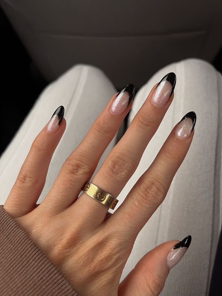 Chic Almond-Shaped Nail Design: Soft Pink with Black Tips and Sparkle.