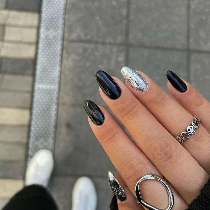 Chic Glossy Black and Silver Almond Nail Design with Elegant Accessories.