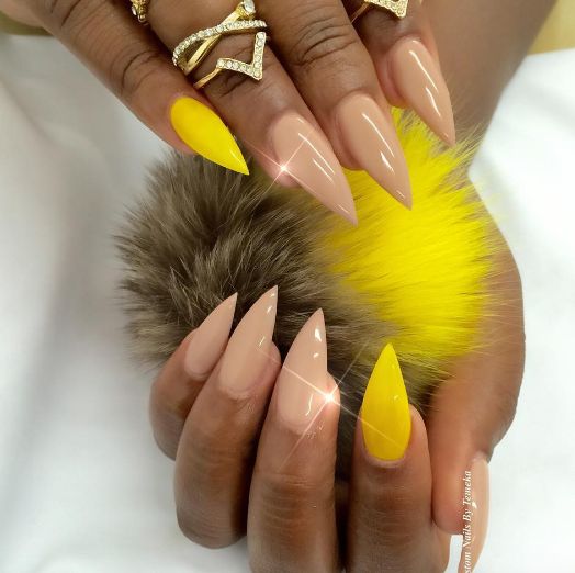 Chic Stiletto Nail Design: Glossy Nude and Vibrant Yellow Blend with Elegant Rings.