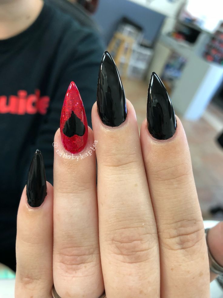 Bold Edgy Nail Design: Glossy Black Meets Vibrant Red with Glitter and Unique Heart Accent.