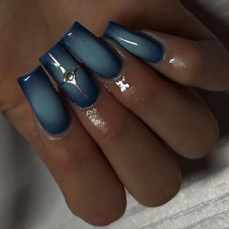 Elegant Ombre Blue Nails with Gradient Shades and Central Gemstone Accent.