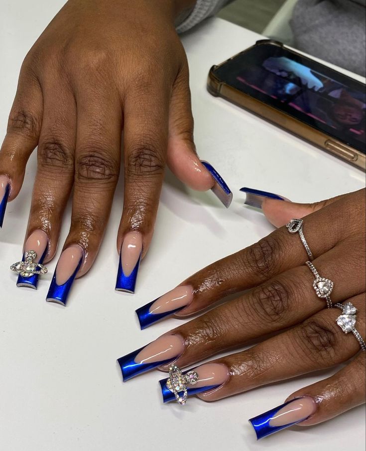 Sophisticated Blue French Tip Nail Design with Nude Base and Stunning Embellishments.