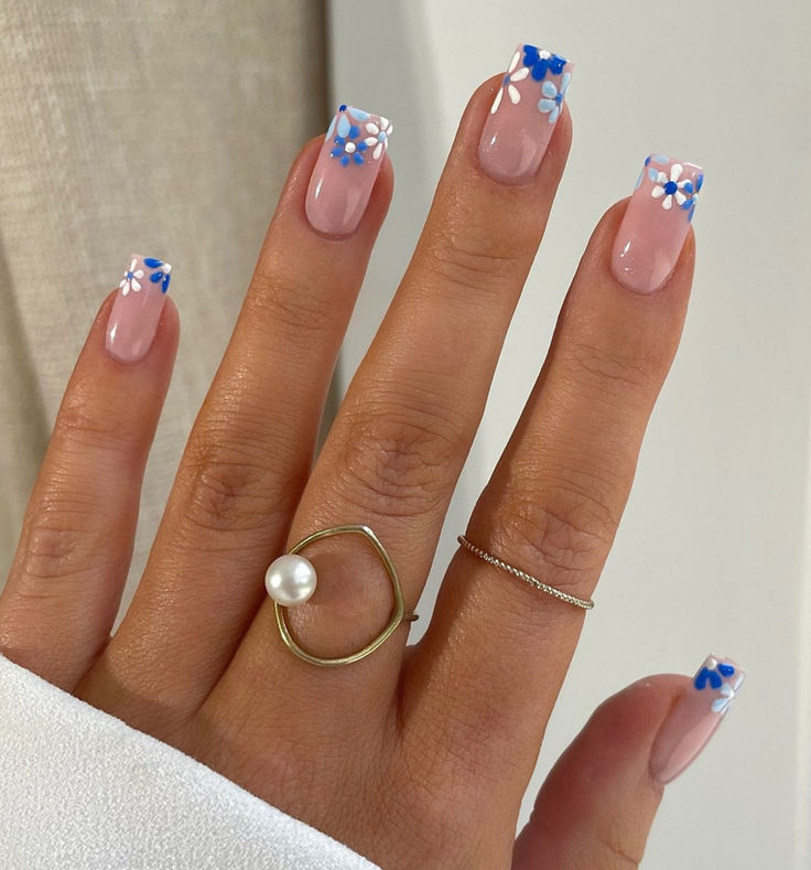 Charming Spring Nail Design: Subtle Pink Base with Floral Accents and Minimalist Jewelry.