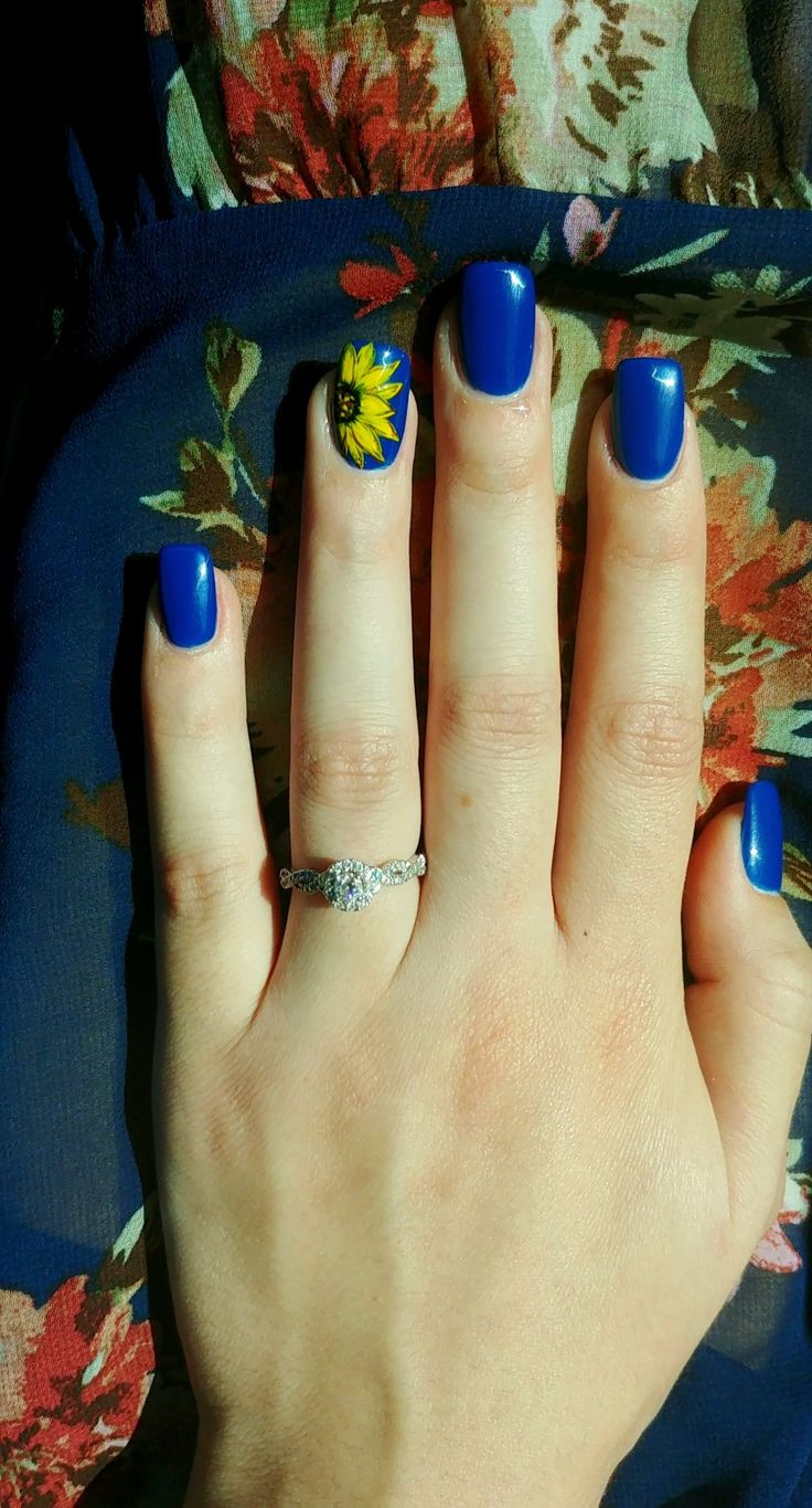 Bold Blue Nails with a Delicate Sunflower Accent for a Chic Manicure.