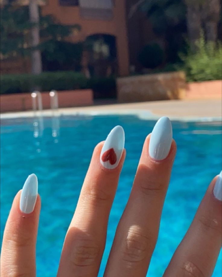 Chic Summer Manicure: Pastel Blue Nails with Playful Red Heart Accents.