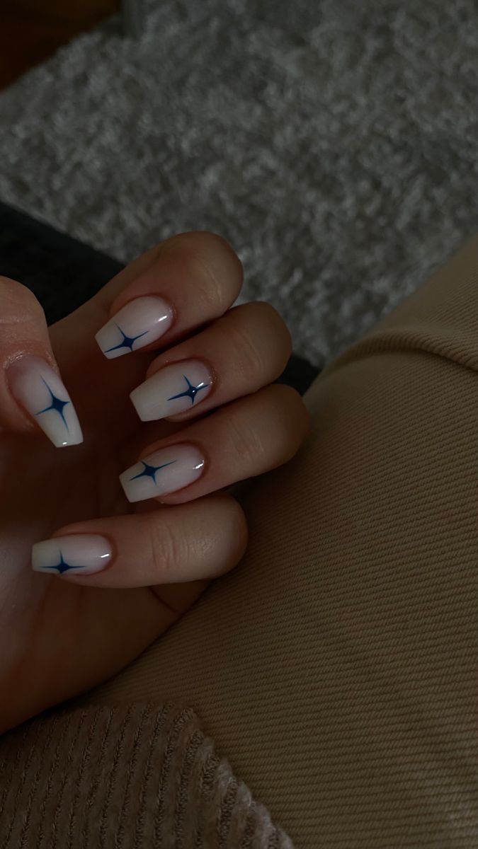 Chic Ombre Nail Design with Soft Pink Base, Polished White Tips, and Blue Starburst Patterns.