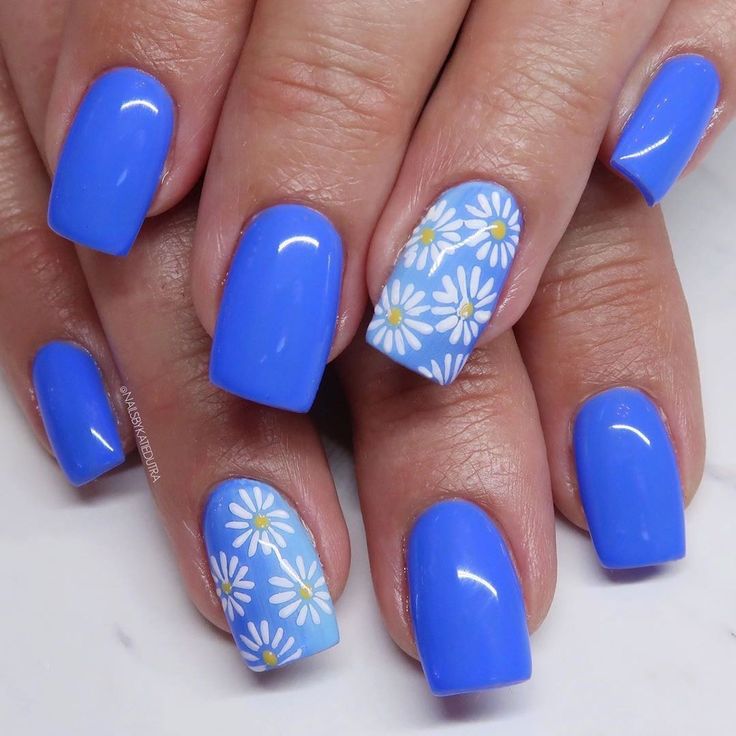 Vibrant Bright Blue Nail Design with Glossy Finish and Accented White Daisy Details.