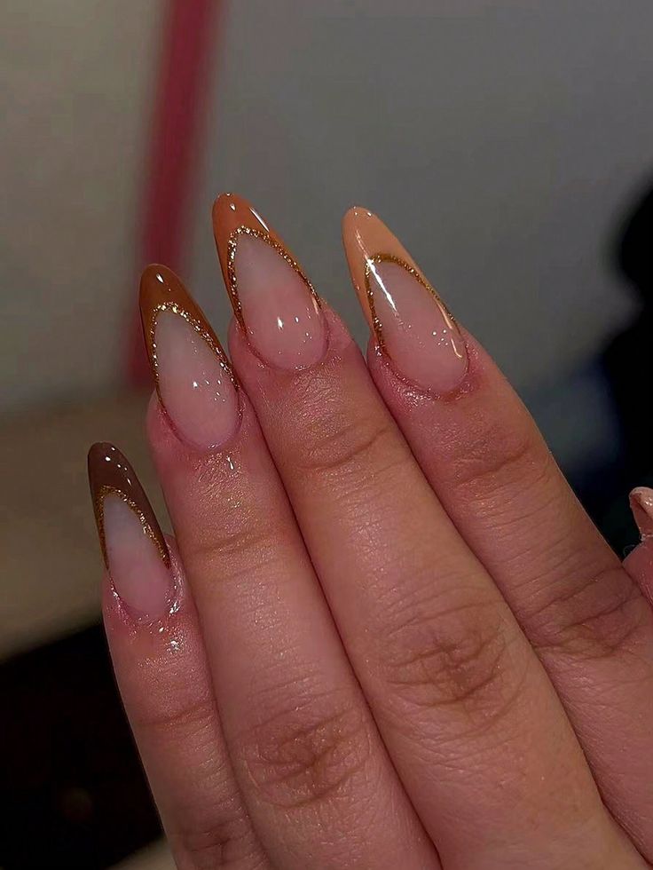 Elegant Almond-Shaped Nails with Gradient Brown to Nude and Gold Accents.