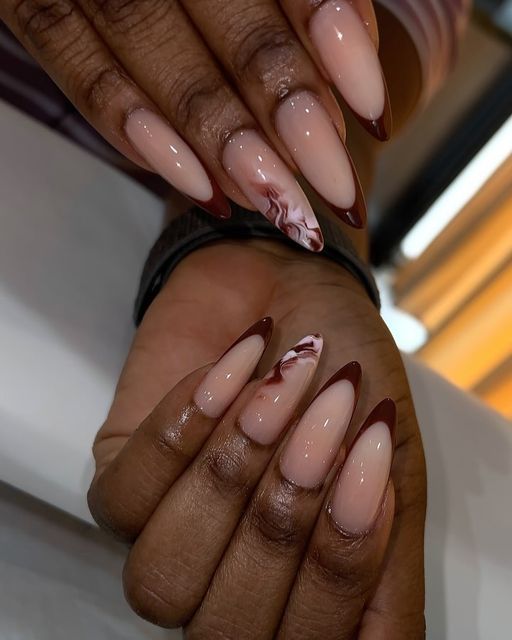 Sophisticated Almond-Shaped Nails with Nude Base, Burgundy Tips, and Marble Accents.