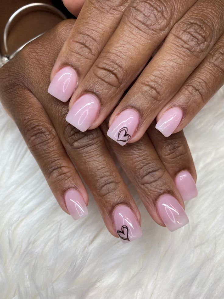 Charming Soft Pink Nail Design with Black Heart Accents and Glossy Finish.