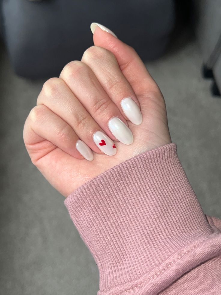 Elegant Almond-Shaped Nails with Neutral Base and Playful Red Heart Accents.