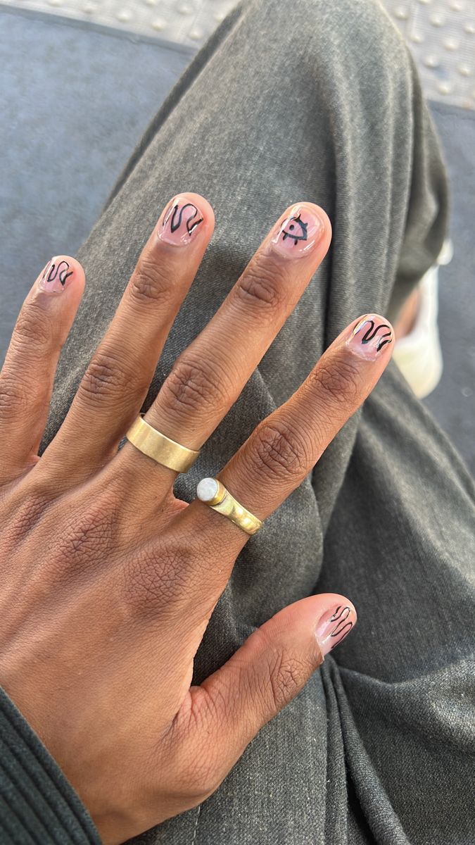 Chic Nude Base Nail Design with Black Abstract Patterns and Stylish Accents